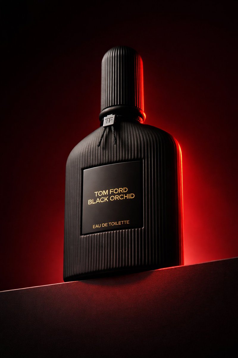 Low angle luxury product photography of a black ribbed glass perfume bottle placed on a dark hor