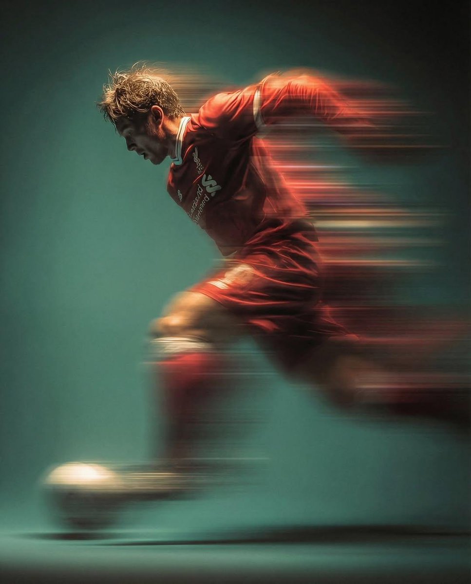 Panning shot of a mysterious soccer player in red proffesional soccer jearsy mid air kicking a b