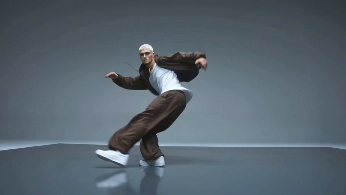 A male street dance expert, white buzz cut, wearing small gold hoop earrings and a gold rope cha