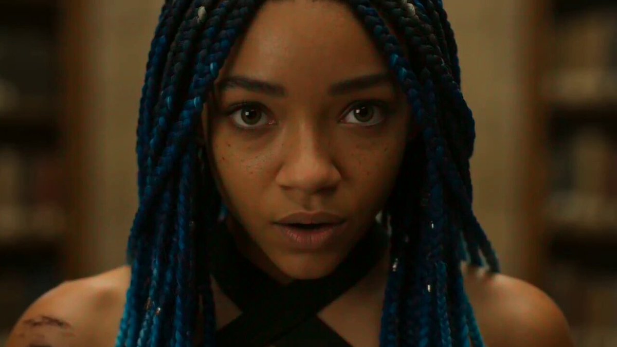 A 19-year-old woman with micro braids dyed deep indigo, warm brown skin, wearing a shredded athl